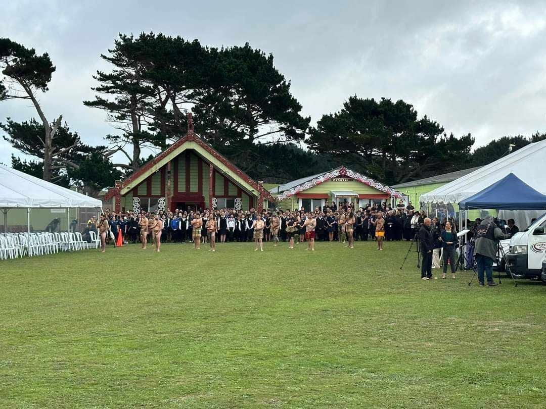 A large crowd and performers gathered in front of the wharenui